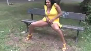 A young lady in a yellow outfit urinates while seated on the bench